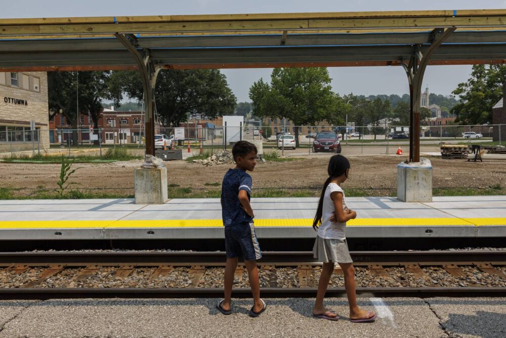 During a stop in Ottumwa, Iowa, Pedro and Yuledy get off the train to stretch their legs and walk along a station platform during the family's 18-hour journey from Denver to Chicago, July 15, 2023.
