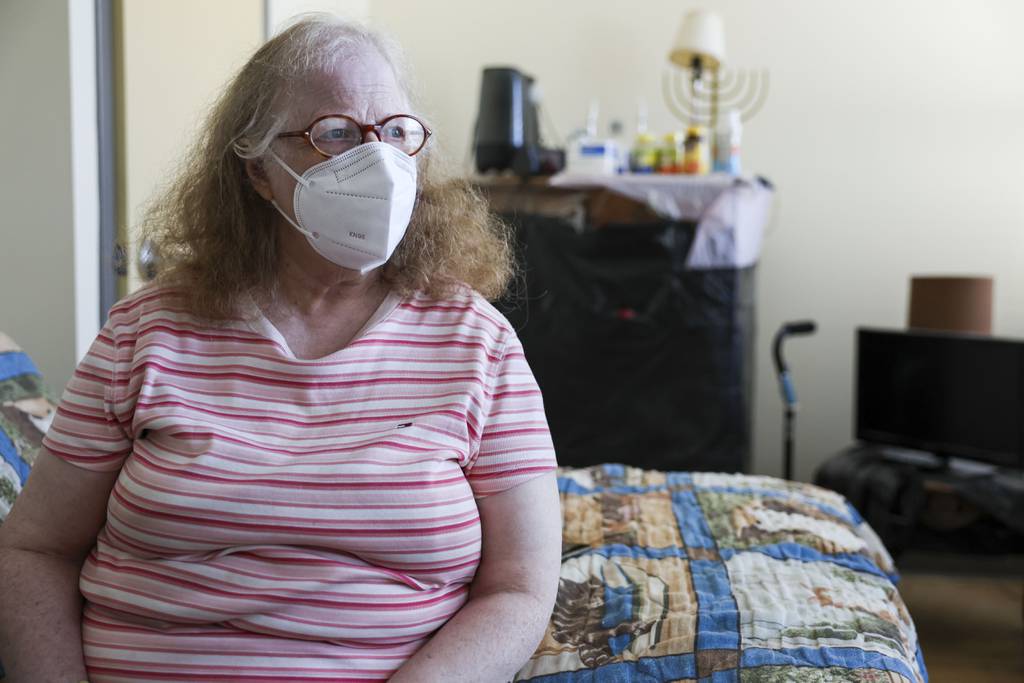 Susan Hoffman sits on her bed in her senior housing unit in the Caroline Hedger Apartments in Rogers Park on Aug. 20, 2023. Hoffman's building has central air conditioning, but the AC is not working in her apartment.