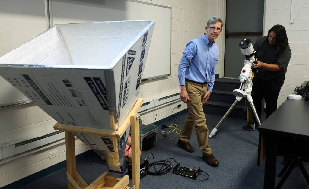 David Schultz, a physics teacher at Maine East High School, left, and student Ethan Yupe prepare a radio telescope and an optical telescope for presentation during a lecture at a meeting of the Chicago Astronomical Society at the Triton College Cernan Earth and Space Center on July 28, 2023, in River Grove.  