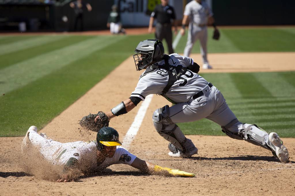 The Athletics' Tyler Wade, left, slides safely across the plate with the winning run ahead of the tag by White Sox catcher Carlos Pérez during the 10th inning on July 1 in Oakland, Calif. The A's won 7-6. 