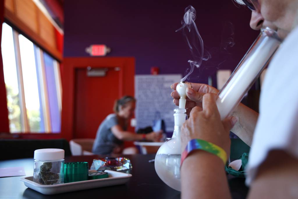 Customers use a bong to smoke marijuana at Okay Cannabis’ consumption lounge in Wheeling on July 29, 2023.