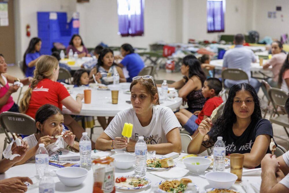 Yuledy, from left, Esperanza and Yolexi eat their last meal with the others at the migrant shelter at Holy Family Catholic Church before leaving for the bus station to travel to Denver on July 13, 2023.