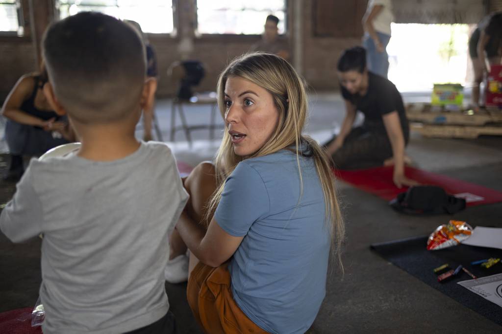 Margarita Quiñones-Peña plays with a young migrant after reading her children’s book aloud at a Pilsen shelter.
