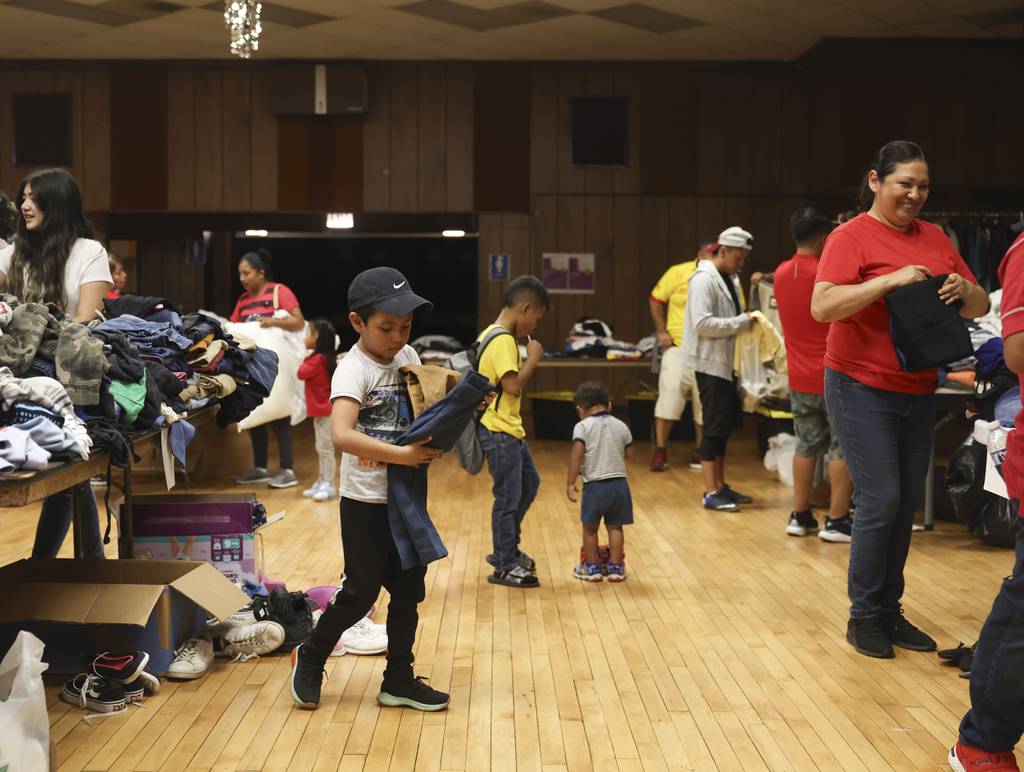 People select donated items during a back-to-school event to help migrant families and local community members at St. Stanislaus Church in the Belmont Cragin area of Chicago on Aug. 12, 2023.