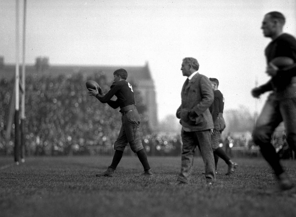 Coach Amos Alonzo Stagg, center, watches Otto Strohmeier for the University of Chicago football team, circa 1920.