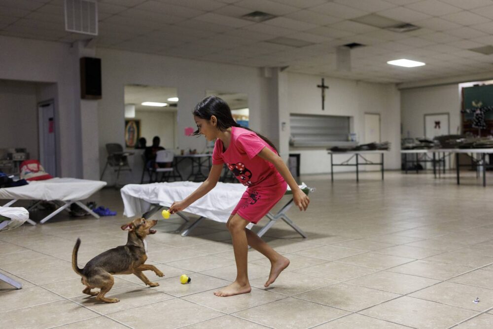 Yuledy plays with Milo while staying at a migrant shelter with her family at Holy Family Catholic Church on July 12, 2023, in El Paso, Texas. 