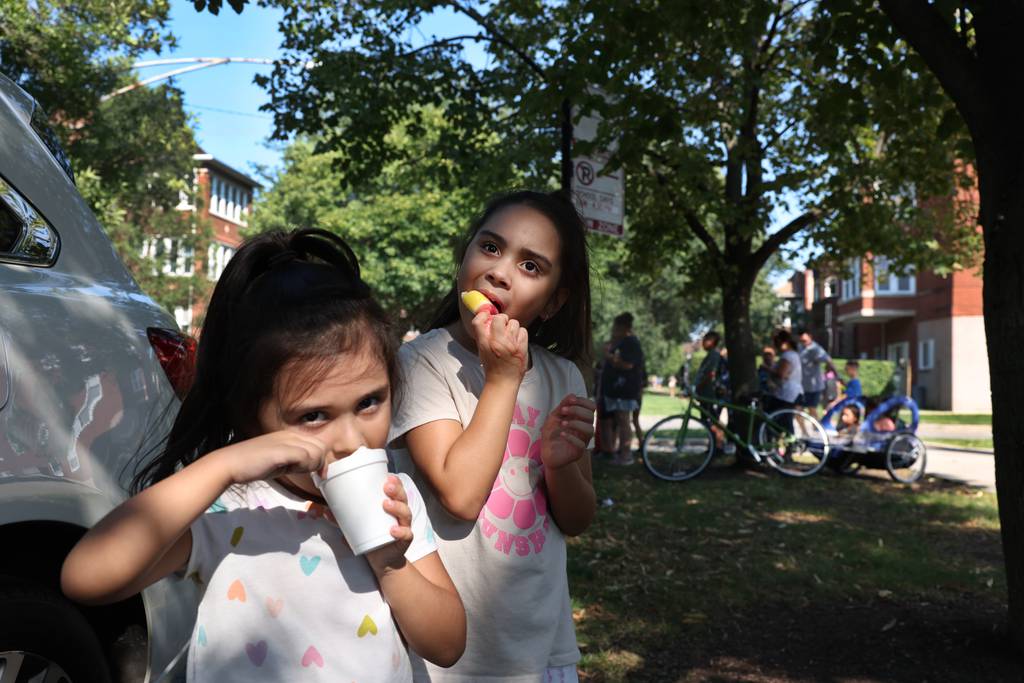 Sisters Oly Aleman, 4, a pre-kindergarten student, and Ely Aleman, 7, a second grader, cool off with frozen treats outside of Portage Park Elementary at the end of a hot school day on Aug. 23, 2023. 