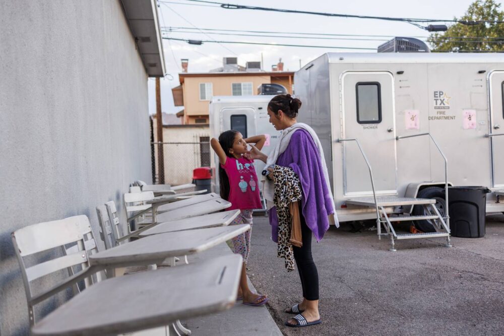 Esperanza talks with Yuledy after conditioning her hair near the showers at the Holy Family Catholic Church migrant shelter on July 12, 2023, in El Paso, Texas. 