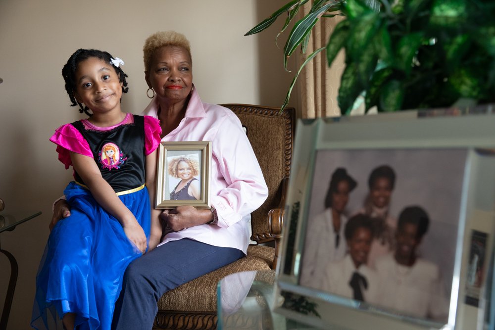 Shirley sitting, holding a picture of her daughter Sonya.