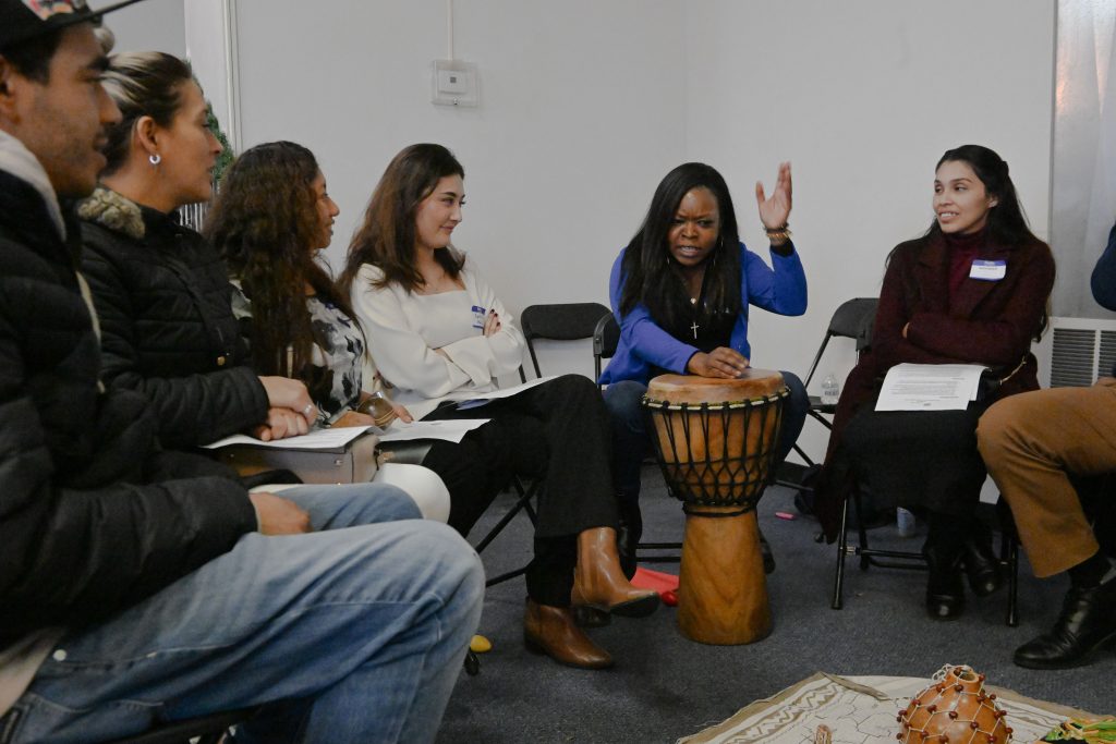 Residents & migrants sit together in a peace circle as one of the peace circle practitioners plays the drums.