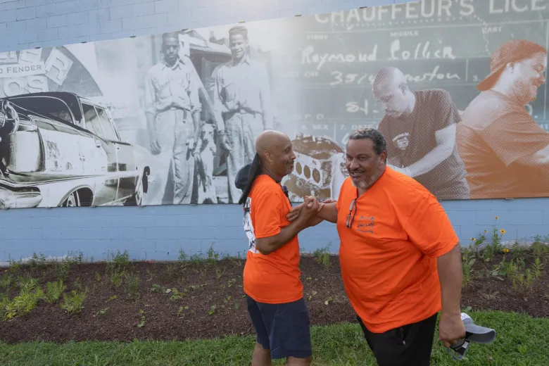 Wayne Jackson and Craig Collier share a moment in front of a mural honoring the 80 year legacy of Collier Brothers Auto Body during the Common Ground Community Car Show & Block Party at the shop’s longtime home on Delmar Boulevard. Lawrence Bryant | St. Louis American