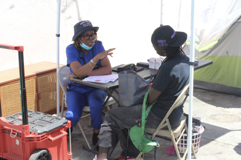 Nurse Practitioner Olusanya provides street-level medical care to an unsheltered patient during a St. John’s Community Health mobile outreach. Photo by Marion Apio